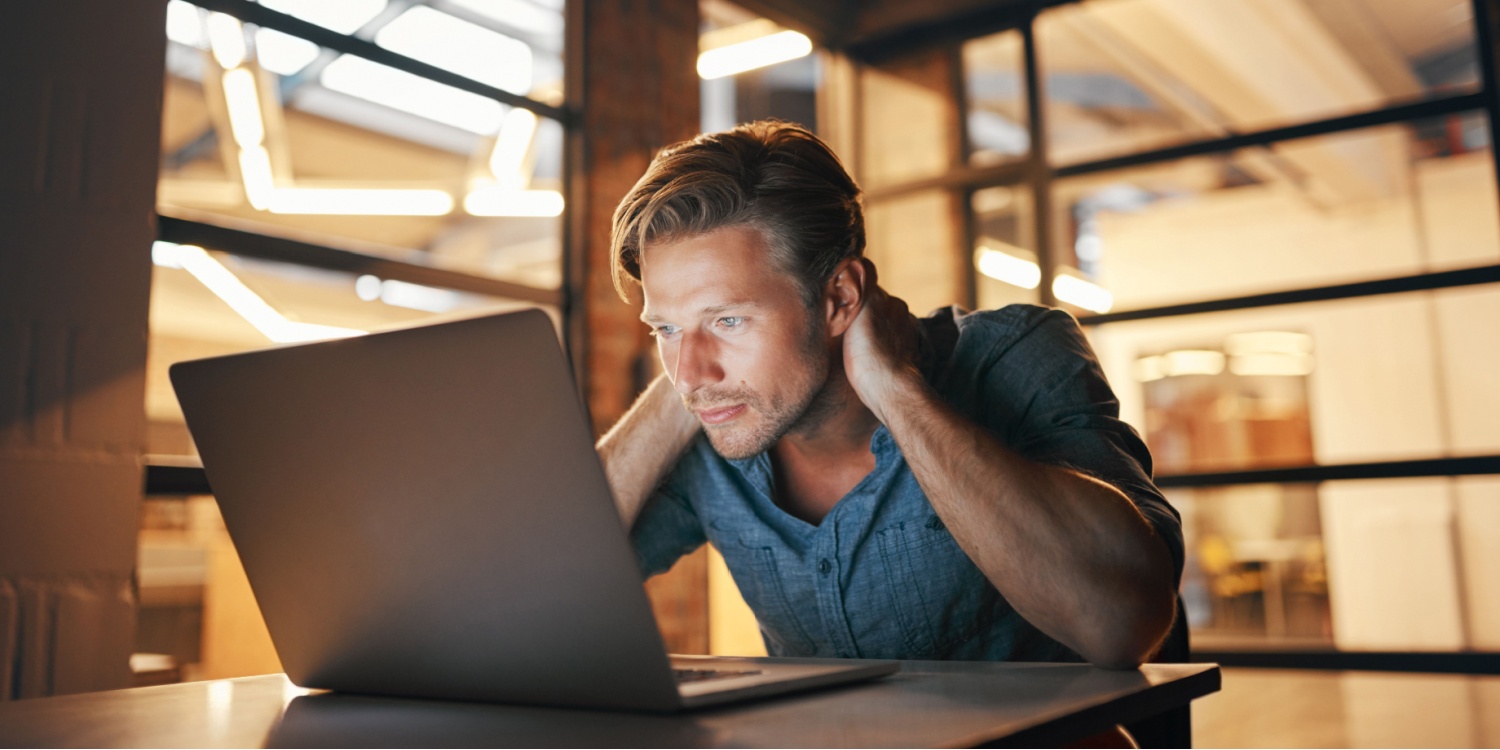 SME owner considers his business's cyber security risk while looking at his laptop with a concerned expression in the office.