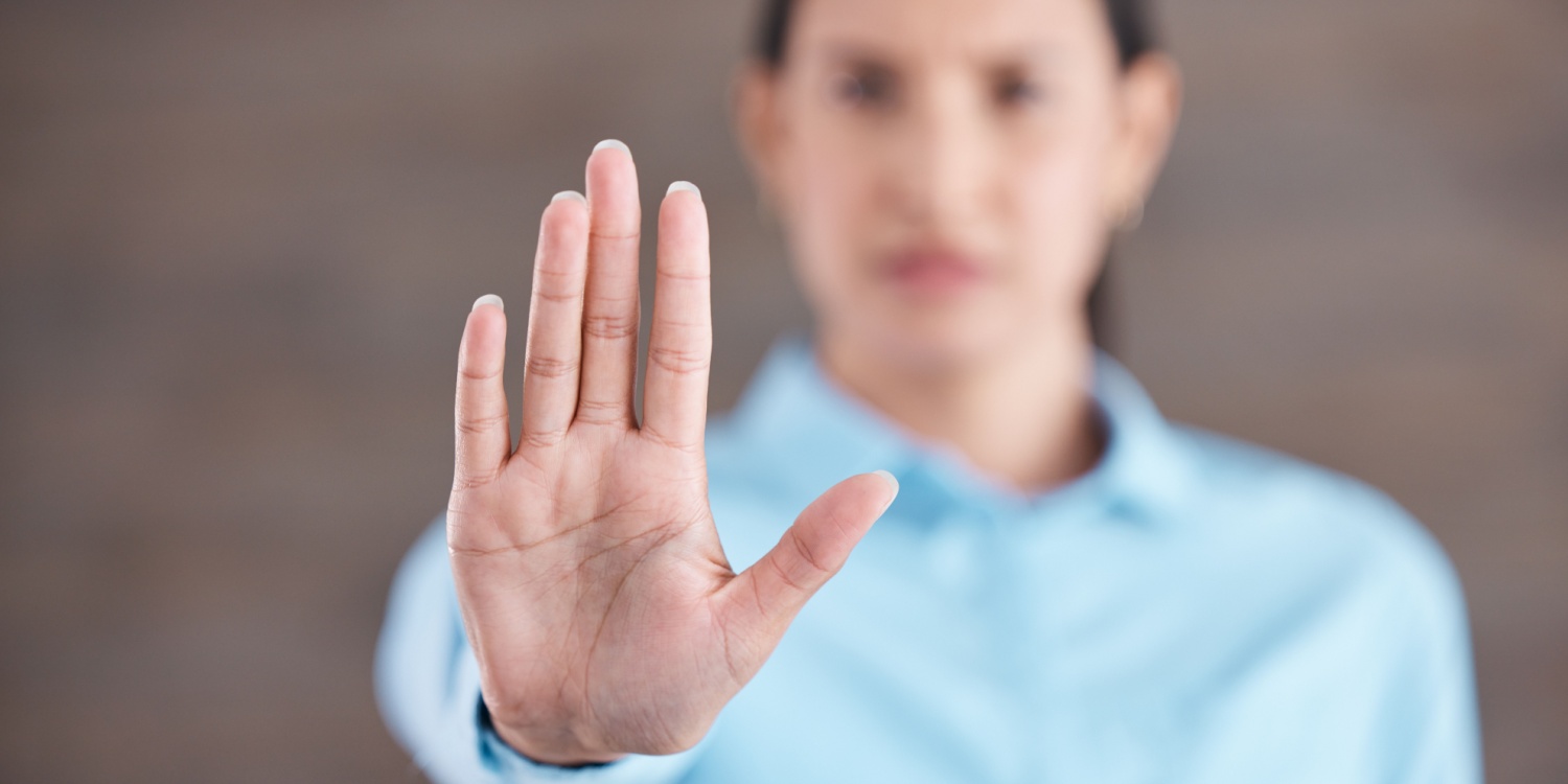 Female business professional holding a hand out in front of her signifying a 'stop' sign.